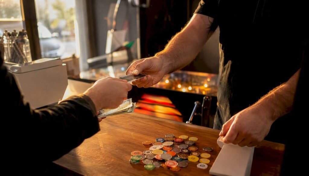 Hands exchanging payment near pinball machine detail